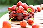 Fresh strawberries in wire basket on wooden table