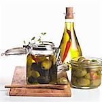 Pickled olives in jars and a bottle of chilli oil