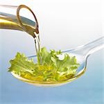 Oil running onto lettuce leaf on spoon