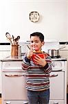 Garçon âgé de six an en remuant le bol devant le poêle dans la cuisine