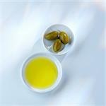 Olive oil and green olives in small dishes (overhead view)