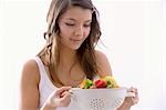 Girl holding a kitchen sieve with fresh fruit