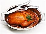 Roast goose in roasting dish, carving knife and fork