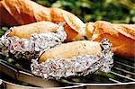 Baked potatoes and baguette on barbecue rack