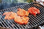 Marinated pork neck steaks on barbecue