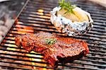 T-bone steak and baked potato on barbecue rack