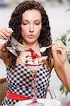 Woman pouring hot raspberries over vanilla ice cream