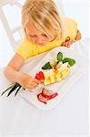 Fille assise à table devant une assiette de fruits