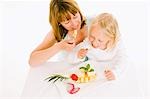 Mother and daughter eating fruit from plate