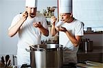 Two chefs tasting soup out of pan