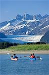 Kayakers kayaking in double sea-kayaks near Juneau in Inside Passage with view of Mendenhall Glacier Alaska