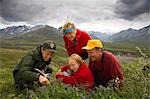 Native Indian US Park Service Ranger shows a family wildflowers on tundra on nature walk Denali National Park Alaska