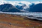 Pair of backpackers hike through the fall landscape toward Long Glacier at Wrangell-St.Elias National Park in Southcentral Alaska.
