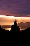 Female Hiker standing on peak overlooking Lynn Canal & Berner's Bay near Juneau Alaska at sunset