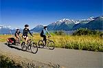 Two women and a man biking on the Bird Point to Girdwood bike trail with a baby stroller during Summer along Turnagain Arm in Southcentral Alaska