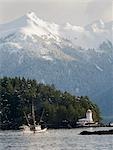 Troller heads out of the Sitka Harbor as it passes by the Rockwell Lighthouse with Mt. Longenbaugh in the background in Southeast Alaska during Winter