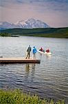 Mature couples canoe on Wonder Lake as others watch from dock with Mt. Mckinley in background, Denali National Park, Alaska