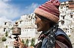 Femme de prière avec le monastère à l'arrière-plan, le monastère Thiksey, Jammu and Kashmir, Ladakh, Inde