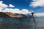 Camera on a tripod at the lakeside with mountains in the background, Pangong Tso Lake, Ladakh, Jammu and Kashmir, India