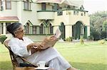 Femme lisant un journal dans une pelouse, New Delhi, Inde