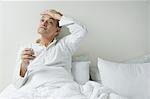 Man sitting on the bed and checking his temperature