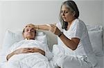 Woman checking a man's temperature in the bedroom