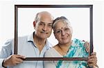 Couple holding a picture frame and smiling