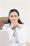 Portrait d'une femme médecin assis devant un ordinateur portable, Gurgaon, Haryana, Inde