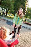 Mutter stossend Tochter auf Schaukel im Green Lake Park im Herbst, Seattle, Washington, USA