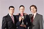 Businesswoman holding trophy with male colleagues, portrait