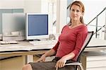 Mid-adult female office worker sitting in cubicle, portrait