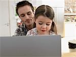 Girl (3-6) using laptop with father at home