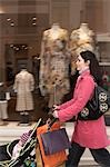 Mother pushing stroller past clothes shop on street