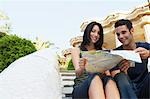 Jeune couple assis sur les escaliers de lecture de carte, portrait