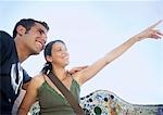 Young couple sitting on stone bench, woman pointing into distance, portrait