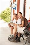 Hikers holding map, sitting on railway platform, portrait