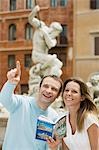 Jeune couple avec guide en regardant monuments sur la rue de Rome, tête et épaules
