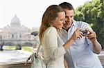 Couple sur le pont en regardant les photos sur l'appareil photo numérique à Rome, Italie