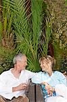 Middle-aged couple sitting outdoors on chairs talking