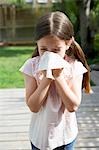Little girl in backyard blowing nose