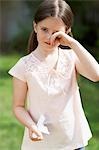 Little girl with cold rubbing eyes in backyard, portrait