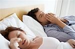 Couple with Colds Lying in Bed