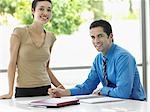 Businessman and businesswoman at office table, portrait