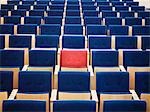 One Red Seat in large group of blue seats in auditorium