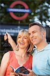 Couple on street with guidebook by London Underground entrance