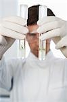 Male lab worker comparing two test tubes with liquid