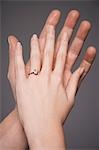 Young couple with hands raised together showing woman's engagement ring, close up on hands