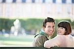 Young couple sitting on bench, head and shoulders, in park