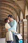 Couple with shopping bags embracing under archway