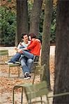 Couple eating snack, sitting on chairs, in park